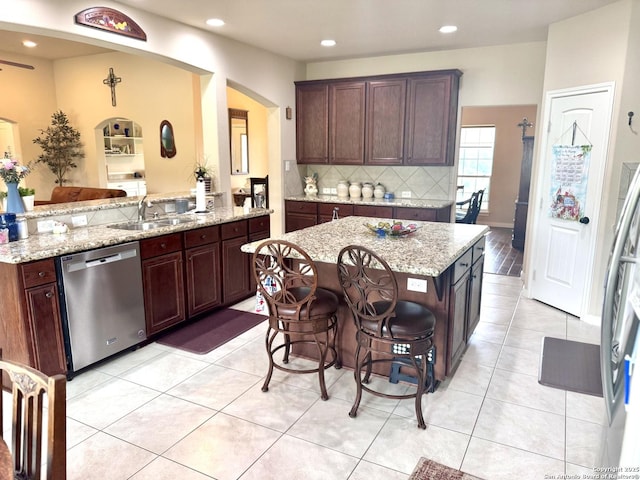 187 Tracks Trl, Center Point, TX 78010 - kitchen featuring stainless steel dishwasher, a sink, arched walkways, light tile patterned floors, and decorative backsplash