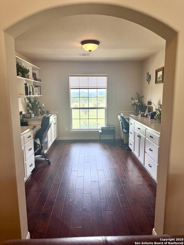 187 Tracks Trl, Center Point, TX 78010 - office area with arched walkways, dark wood-style floors, built in study area, and baseboards