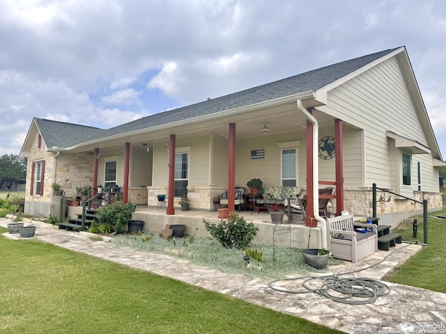 187 Tracks Trl, Center Point, TX 78010 - view of front of house with covered porch, stone siding, a front yard, and a shingled roof