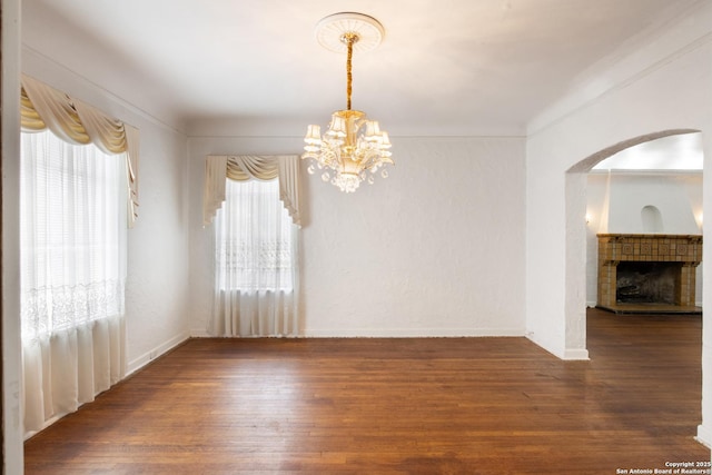 2150 W Summit Ave, San Antonio, TX 78201 - empty room with a chandelier, arched walkways, wood finished floors, a fireplace, and baseboards