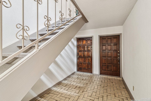 2300 Nacogdoches Rd Unit 164R, San Antonio, TX 78209 - entrance foyer featuring baseboards, a textured ceiling, brick patterned flooring, and stairway