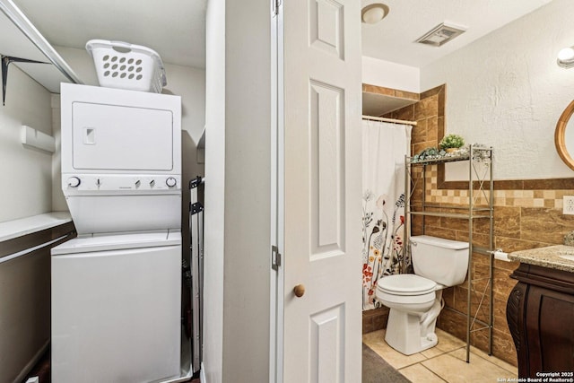 2300 Nacogdoches Rd Unit 164R, San Antonio, TX 78209 - bathroom with stacked washer / dryer, tile walls, toilet, vanity, and tile patterned floors