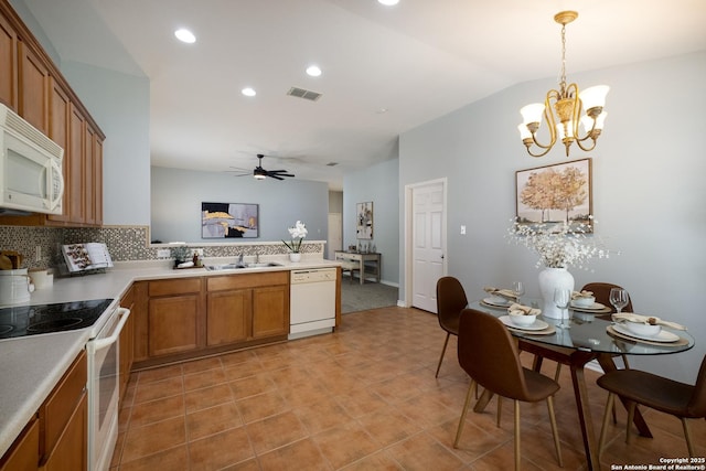 9911 Sable Arrow, San Antonio, TX 78251 - kitchen with white appliances, brown cabinetry, a peninsula, tasteful backsplash, and a chandelier