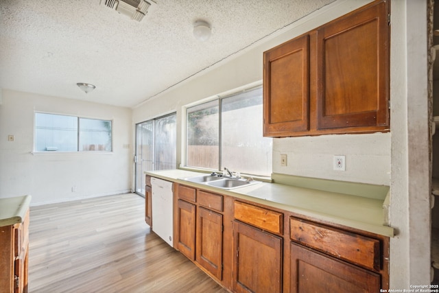 1324 Longmont, San Antonio, TX 78245 - kitchen with a sink, white dishwasher, a textured ceiling, light wood-style floors, and light countertops