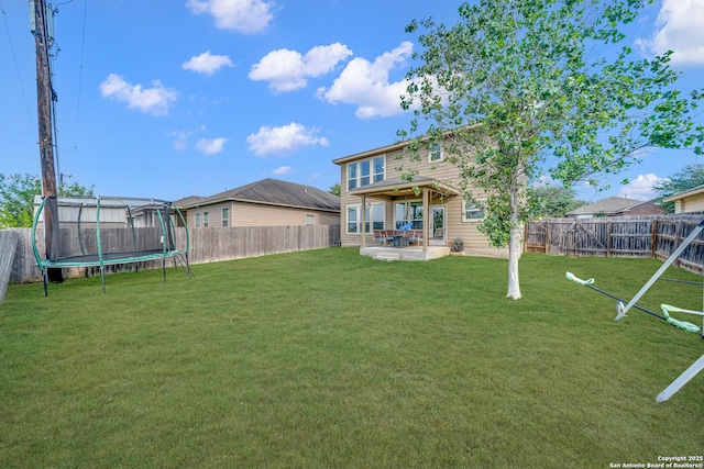 7702 Bit Cir, Elmendorf, TX 78112 - back of property featuring a trampoline and a patio area
