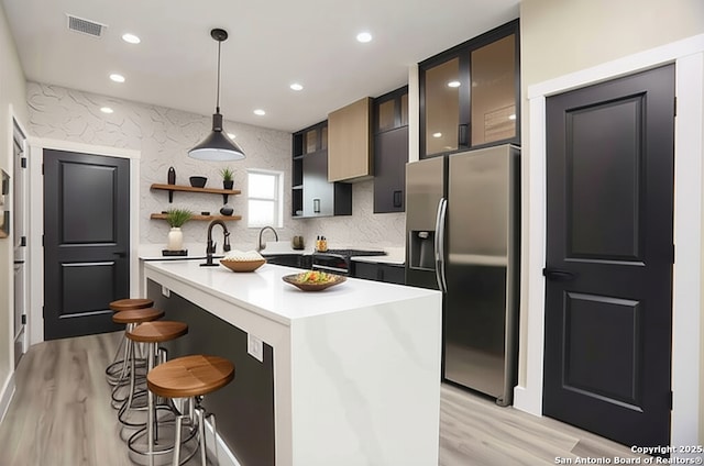 130 E Lachapelle, San Antonio, TX 78204 - kitchen with stainless steel fridge with ice dispenser, light wood-style flooring, a breakfast bar, light countertops, and recessed lighting