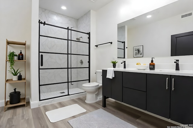130 E Lachapelle, San Antonio, TX 78204 - full bathroom with toilet, double vanity, a shower stall, wood finished floors, and recessed lighting