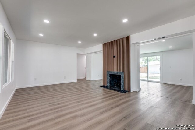 602 John Page, San Antonio, TX 78228 - unfurnished living room with light wood-style floors, recessed lighting, a fireplace with raised hearth, and baseboards