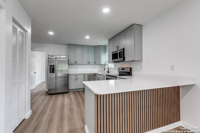 602 John Page, San Antonio, TX 78228 - kitchen with stainless steel appliances, gray cabinetry, a peninsula, light wood-style flooring, and recessed lighting