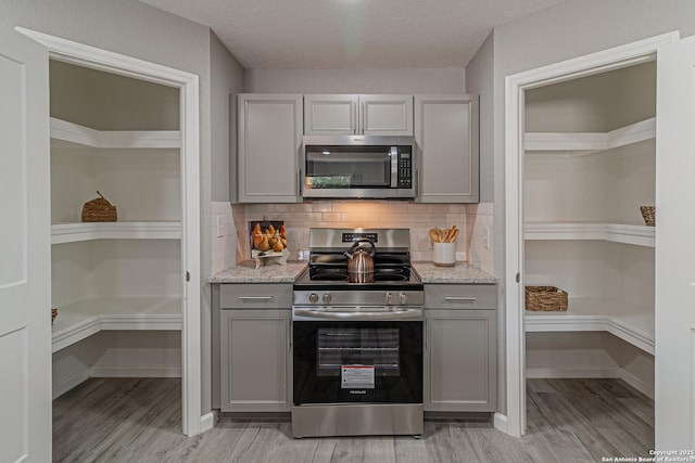 4935 Bartmer Ave, San Antonio, TX 78228 - kitchen with appliances with stainless steel finishes, gray cabinets, light wood-style floors, tasteful backsplash, and a textured ceiling