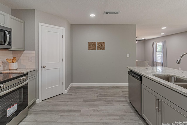 4935 Bartmer Ave, San Antonio, TX 78228 - kitchen featuring stainless steel appliances, gray cabinets, light wood-style floors, light stone counters, and recessed lighting
