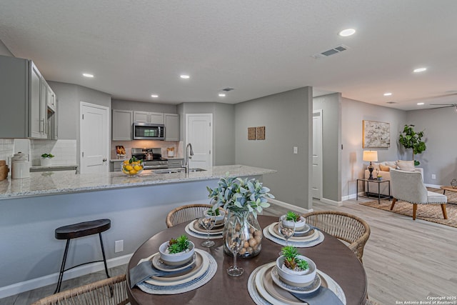 4935 Bartmer Ave, San Antonio, TX 78228 - kitchen featuring appliances with stainless steel finishes, light stone counters, light wood-type flooring, gray cabinetry, and recessed lighting