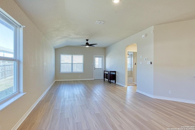 13351 Welsh Pony, San Antonio, TX 78254 - unfurnished living room with arched walkways, a ceiling fan, light wood-style floors, vaulted ceiling, and baseboards