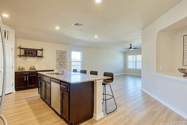 13351 Welsh Pony, San Antonio, TX 78254 - kitchen featuring stainless steel dishwasher, a kitchen breakfast bar, light wood-style floors, a sink, and light stone counters