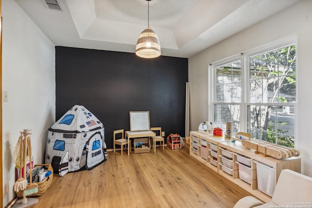 101 Country Ln, Castroville, TX 78009 - playroom featuring light wood finished floors, a tray ceiling, and a textured ceiling