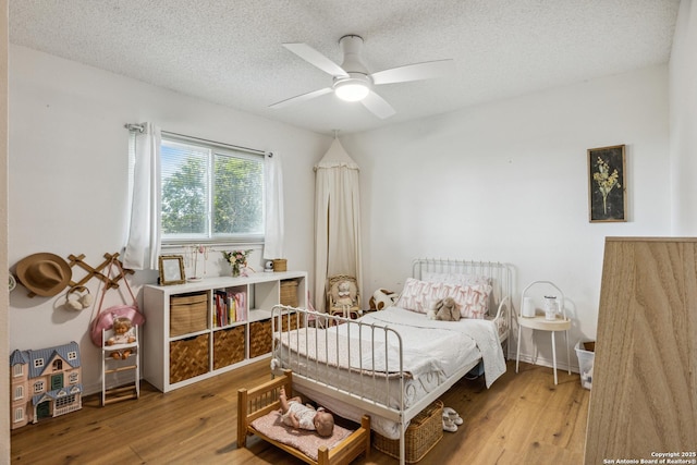 101 Country Ln, Castroville, TX 78009 - bedroom featuring wood finished floors, a textured ceiling, and a ceiling fan