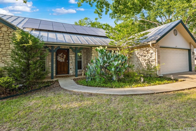 101 Country Ln, Castroville, TX 78009 - view of front of home featuring a standing seam roof, roof mounted solar panels, a front lawn, a garage, and stone siding