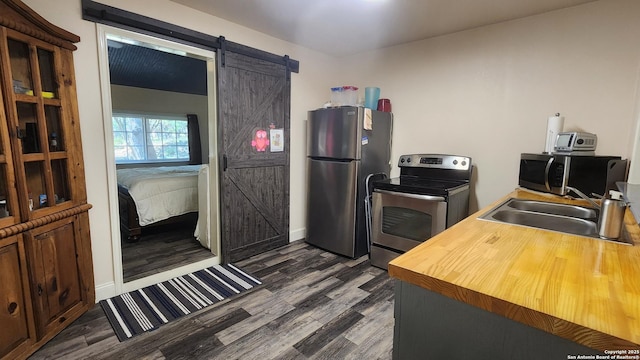 12151 Park Road 37, Lakehills, TX 78063 - kitchen featuring stainless steel appliances, a sink, a barn door, wooden counters, and dark wood finished floors