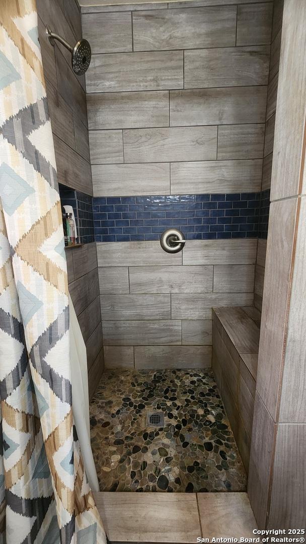 12151 Park Road 37, Lakehills, TX 78063 - bathroom with a tile shower and stone finish flooring