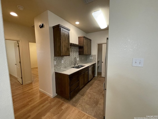 104 W W Unit 104, Comfort, TX 78013 - kitchen with a sink, dark brown cabinetry, tasteful backsplash, light countertops, and light wood-style floors