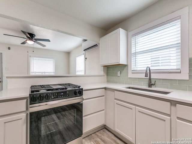 815 Flanders, San Antonio, TX 78211 - kitchen with gas stove, a sink, tasteful backsplash, a wall unit AC, and light countertops