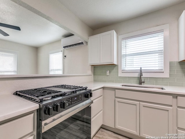 815 Flanders, San Antonio, TX 78211 - kitchen with range with gas stovetop, a sink, a wall unit AC, a ceiling fan, and light countertops