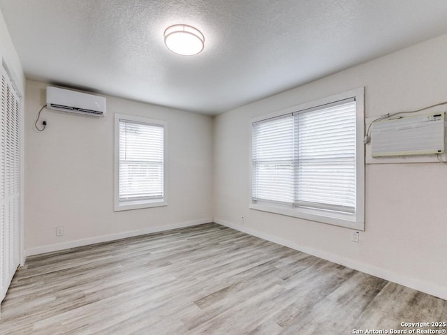 815 Flanders, San Antonio, TX 78211 - spare room with a wall mounted air conditioner, light wood-style flooring, a textured ceiling, baseboards, and a wall mounted AC
