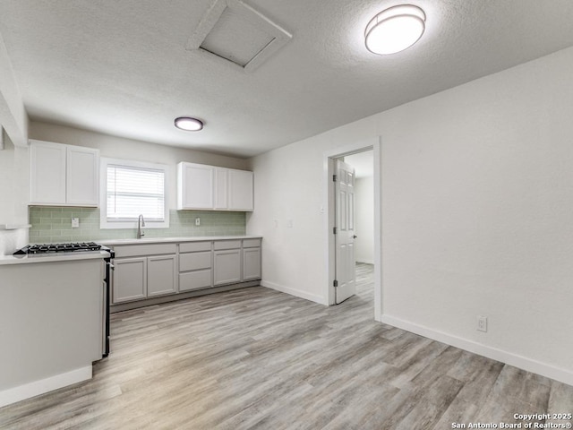 815 Flanders, San Antonio, TX 78211 - kitchen featuring light wood finished floors, backsplash, a textured ceiling, baseboards, and light countertops