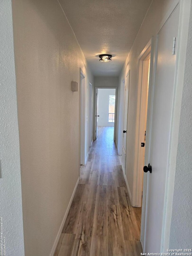 7401 Old Spanish Trl, Live Oak, TX 78233 - corridor with light wood-style floors, baseboards, a textured wall, and a textured ceiling