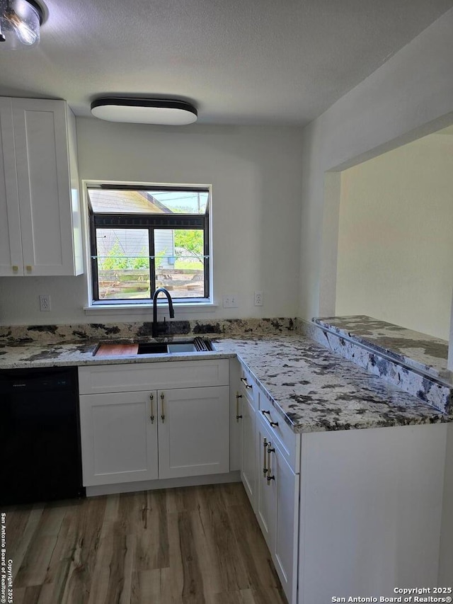 7401 Old Spanish Trl, Live Oak, TX 78233 - kitchen with black dishwasher, light wood-type flooring, a peninsula, a sink, and white cabinets