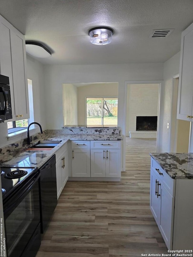 7401 Old Spanish Trl, Live Oak, TX 78233 - kitchen with black appliances, a sink, light stone countertops, light wood-style floors, and a textured ceiling