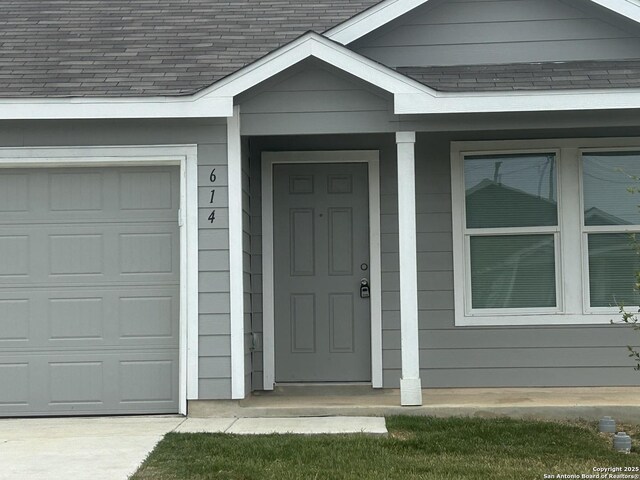 614 Agave, Jourdanton, TX 78026 - entrance to property with a shingled roof, concrete driveway, a garage, and covered porch
