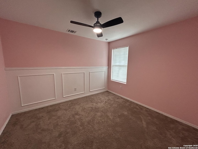 614 Agave, Jourdanton, TX 78026 - empty room featuring ceiling fan, wainscoting, and dark colored carpet