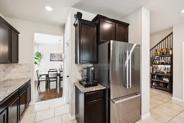 32003 Cast Iron, Bulverde, TX 78163 - kitchen with freestanding refrigerator, light tile patterned floors, dark brown cabinetry, a chandelier, and decorative backsplash