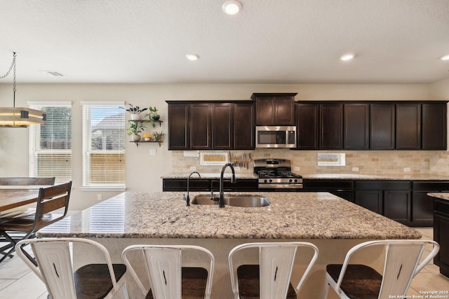 32003 Cast Iron, Bulverde, TX 78163 - kitchen with stainless steel appliances, a sink, light stone countertops, a kitchen island with sink, and dark brown cabinets