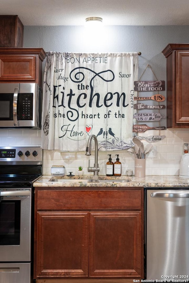 5802 Branch Vly, San Antonio, TX 78242 - kitchen with appliances with stainless steel finishes, a sink, tasteful backsplash, light stone countertops, and a textured wall
