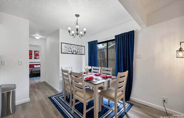 9630 NW Simplicity Dr, San Antonio, TX 78245 - dining space with wood finished floors, a chandelier, a textured ceiling, and baseboards