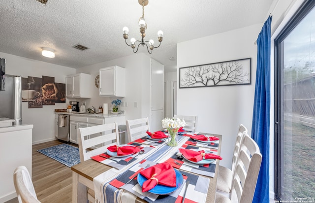 9630 NW Simplicity Dr, San Antonio, TX 78245 - dining space featuring a chandelier, light wood-type flooring, a textured ceiling, and baseboards
