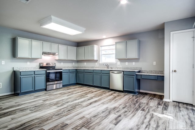 510 Hampton Cv, Boerne, TX 78006 - kitchen with appliances with stainless steel finishes, under cabinet range hood, light wood-type flooring, light countertops, and a sink