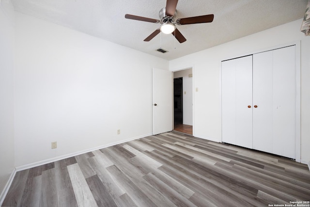 7035 Forest Mdw, San Antonio, TX 78240 - unfurnished bedroom featuring wood finished floors, a closet, a ceiling fan, baseboards, and a textured ceiling