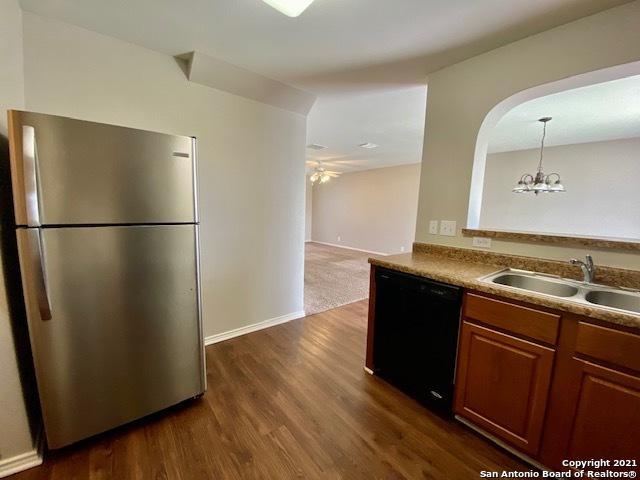 6926 Lunar Way, San Antonio, TX 78109 - kitchen with freestanding refrigerator, black dishwasher, a sink, dark wood-style floors, and a ceiling fan