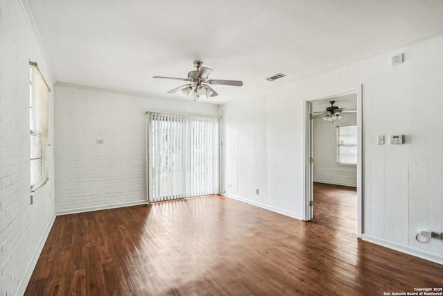 7735 Mocking Bird Ln, San Antonio, TX 78229 - empty room featuring ornamental molding, ceiling fan, healthy amount of natural light, wood finished floors, and brick wall