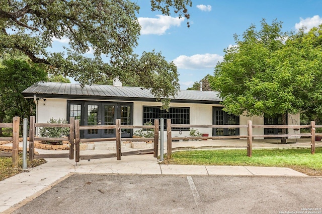 7735 Mocking Bird Ln, San Antonio, TX 78229 - view of front of property featuring french doors, metal roof, stucco siding, and a chimney