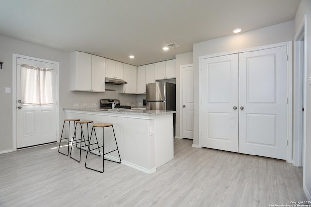 10787 Giacconi, Converse, TX 78109 - kitchen with freestanding refrigerator, under cabinet range hood, a peninsula, light wood-style flooring, and white cabinetry
