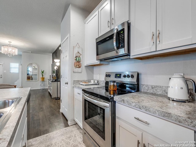 607 Pleasanton Spg, San Antonio, TX 78221 - kitchen with appliances with stainless steel finishes, light countertops, dark wood-type flooring, and white cabinets