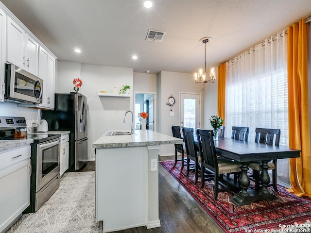 607 Pleasanton Spg, San Antonio, TX 78221 - kitchen with stainless steel appliances, a sink, a chandelier, an island with sink, and light wood finished floors