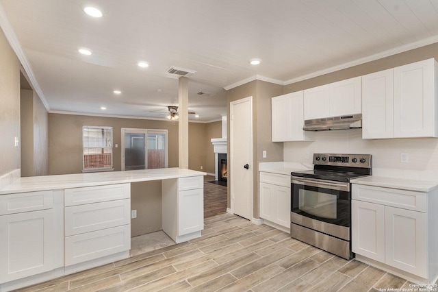 4543 Stradford, San Antonio, TX 78217 - kitchen featuring electric range, under cabinet range hood, crown molding, a warm lit fireplace, and white cabinets