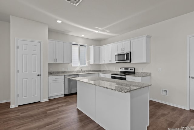 4068 Paddock Trl, Seguin, TX 78155 - kitchen featuring appliances with stainless steel finishes, a sink, white cabinetry, dark wood-type flooring, and a center island