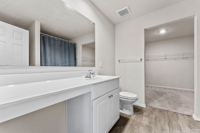 7115 Mesa Clfs, Converse, TX 78109 - bathroom featuring toilet, a spacious closet, vanity, wood finished floors, and a shower with shower curtain