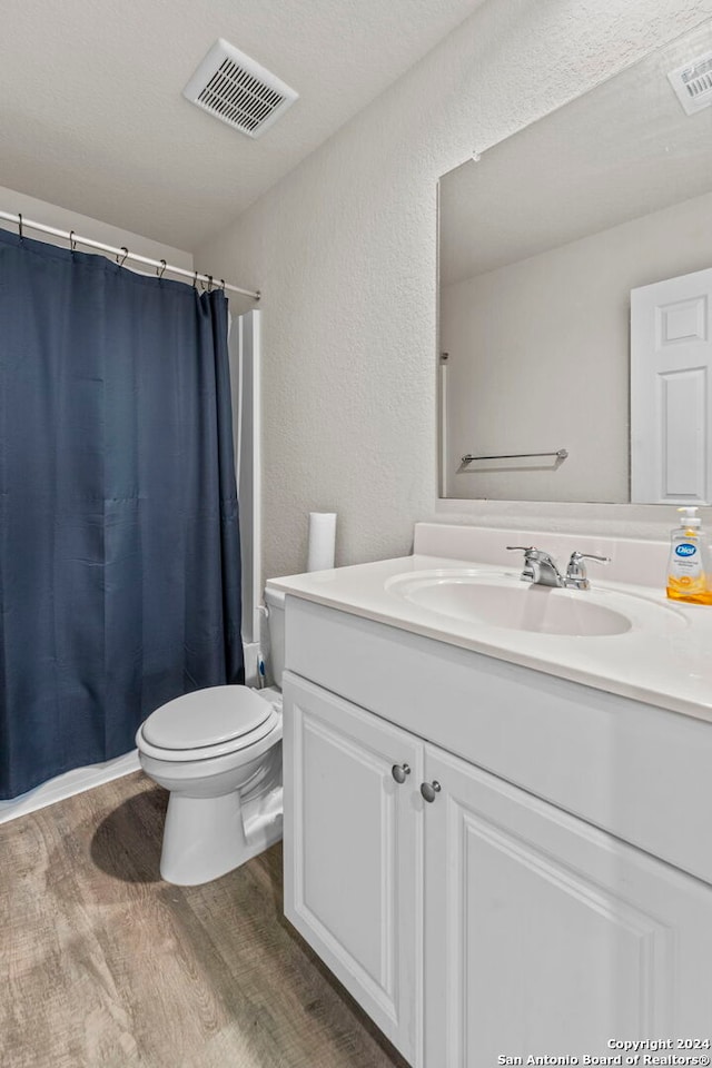 7115 Mesa Clfs, Converse, TX 78109 - bathroom featuring wood finished floors, vanity, toilet, a shower with shower curtain, and a textured wall